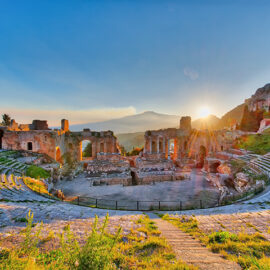 Ancient theatre of Taormina with Etna erupting volcano at sunset