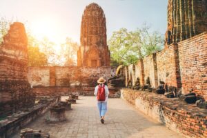 Traveler walking through ancient temple ruins at sunset