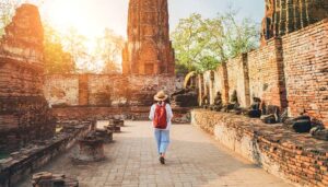 Traveler walking through ancient temple ruins at sunset